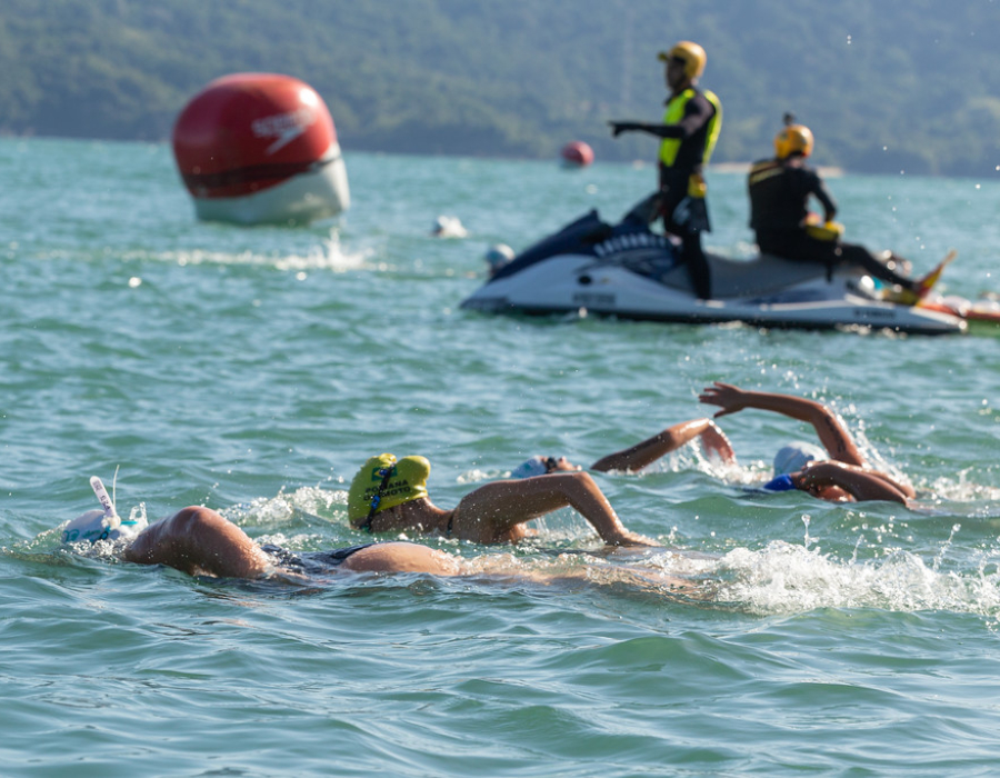 Nadadores à frente com pessoas especializadas em salvar de afogamentos em um jet ski